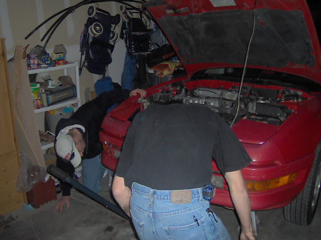 Red 1996 Ford Probe with hood open, people working on engine