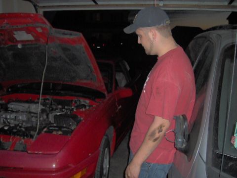 1996 Ford Probe - A man stands next to a red coupe with its hood open, parked in a garage.
