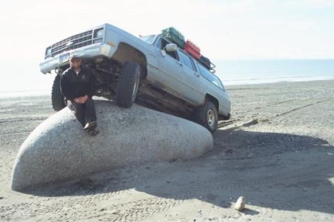 1990 Chevrolet Suburban - Man poses on a rock as his 1990 Chevrolet Suburban is positioned on top of it.
