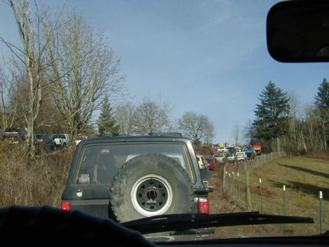 1994 Ford Explorer - A convoy of off-road vehicles navigates a muddy track during an event.