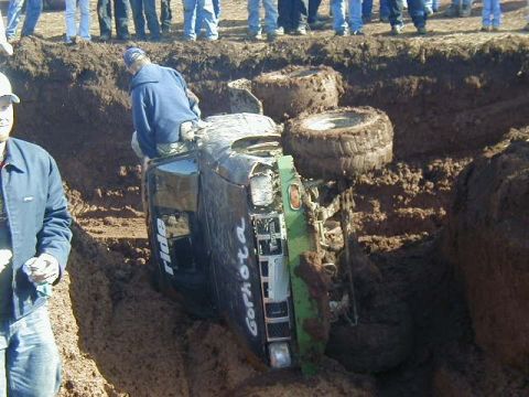 1994 Ford Explorer - An off-road vehicle is stuck in a mud pit, with onlookers standing on the edge.
