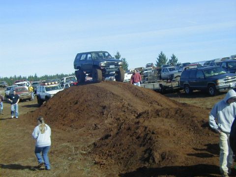 1994 Ford Explorer - Several off-road vehicles are gathered at a mud pit event with spectators present.