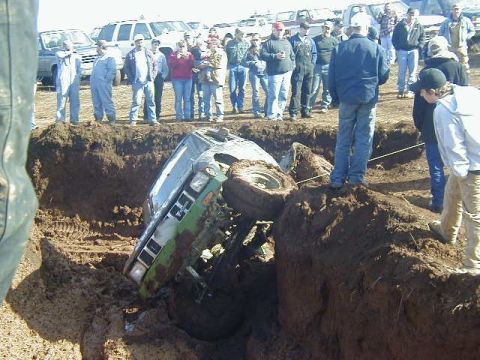 1994 Ford Explorer - A crowd gathers to watch a green pickup truck that has become stuck in a deep pit.