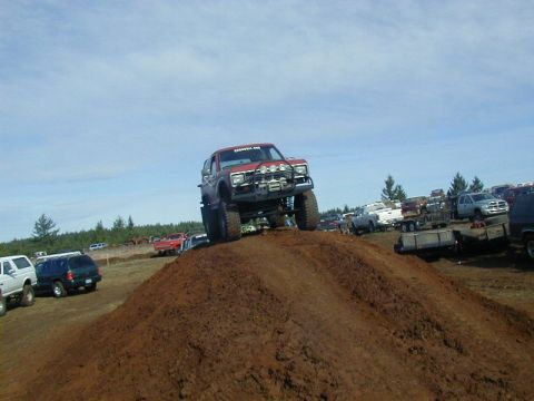 1994 Ford Explorer - A red SUV navigates a dirt obstacle at an outdoor event with other vehicles in the background.