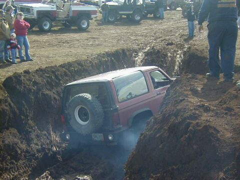 1994 Ford Explorer - A red 1989 Ford Bronco II is stuck in a deep trench, with spectators watching from the side.