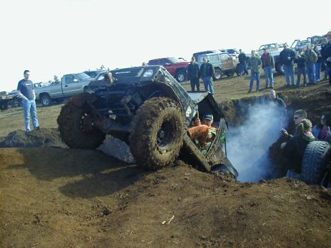 1994 Ford Explorer - A heavily modified off-road vehicle is stuck in a ditch while spectators watch.