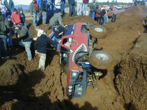 1994 Ford Explorer - Off-road vehicle overturned in a mud pit, surrounded by onlookers.