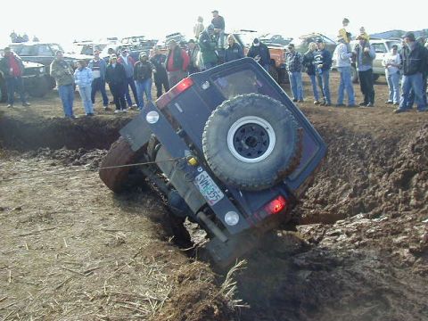 1994 Ford Explorer - A 1994 Ford Explorer is stuck in a deep mud pit during an off-road event, with spectators observing.