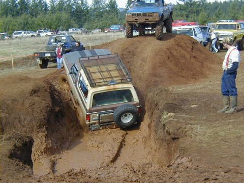 1994 Ford Explorer - A brown SUV navigates a challenging mud obstacle during an off-road event.
