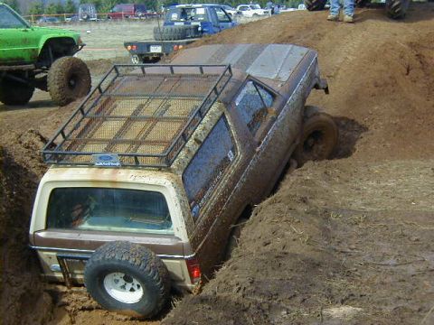 1994 Ford Explorer - Multiple off-road vehicles navigate a muddy terrain during an event.