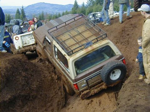 1994 Ford Explorer - Two off-road vehicles struggle in deep mud during an event.