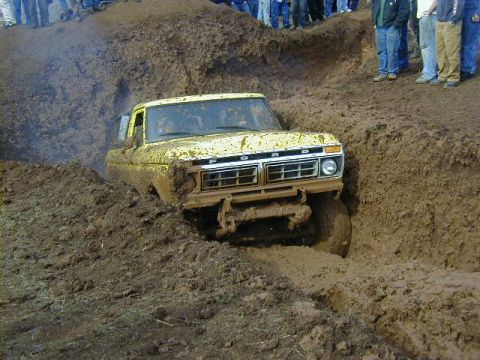 1994 Ford Explorer - A yellow Ford truck navigates a deep mud pit during an event.