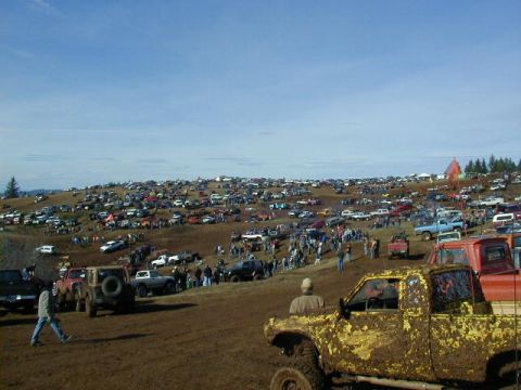 1994 Ford Explorer - A large gathering of vehicles at a muddy event, with numerous trucks and SUVs parked and driving on a hillside.