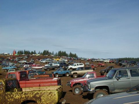 1994 Ford Explorer - A large gathering of trucks and SUVs are parked on a muddy field, likely for an off-road event.