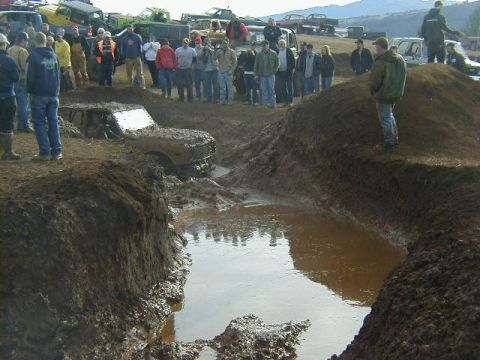 1994 Ford Explorer - A group of off-road vehicles are stuck in the mud during an event, with onlookers observing the scene.