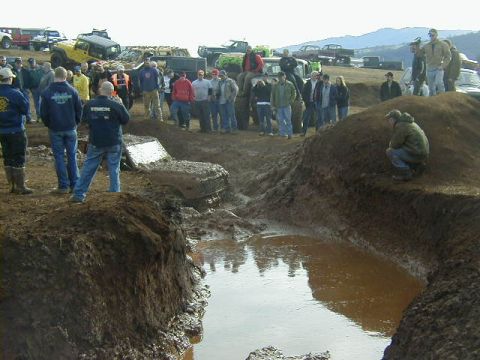 1994 Ford Explorer - Spectators observe off-road vehicles navigating a challenging muddy terrain during an event.