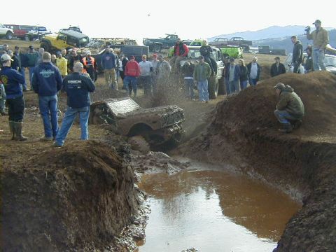 1994 Ford Explorer - Spectators gather to watch an off-road vehicle navigate a muddy obstacle course during an event.