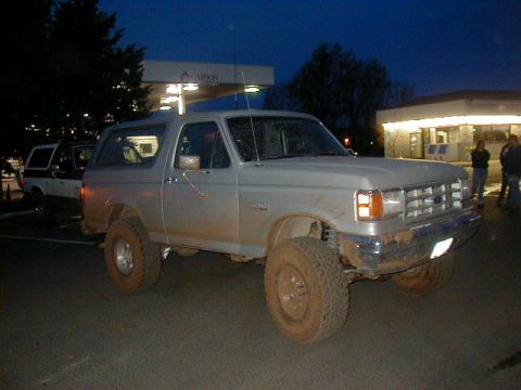 1994 Ford Explorer - A silver Ford Bronco, covered in mud, is parked at a gas station with another vehicle behind it.