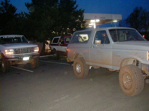 1994 Ford Explorer - Several muddy Ford Broncos are parked together outside a gas station at dusk.