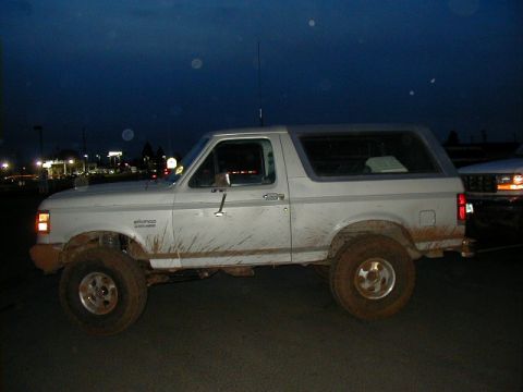 1994 Ford Explorer - Mud-splattered white Ford Bronco parked outdoors at twilight, with another vehicle visible to the right.