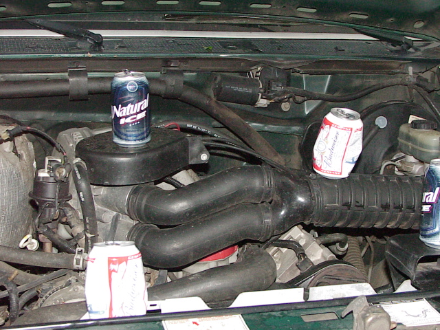 Engine bay with Natural Ice and Budweiser beer cans set on components for scale