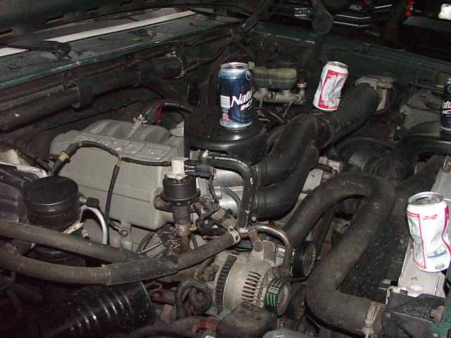 Engine bay of a 1994 Ford F-150 with three cans of beer on top