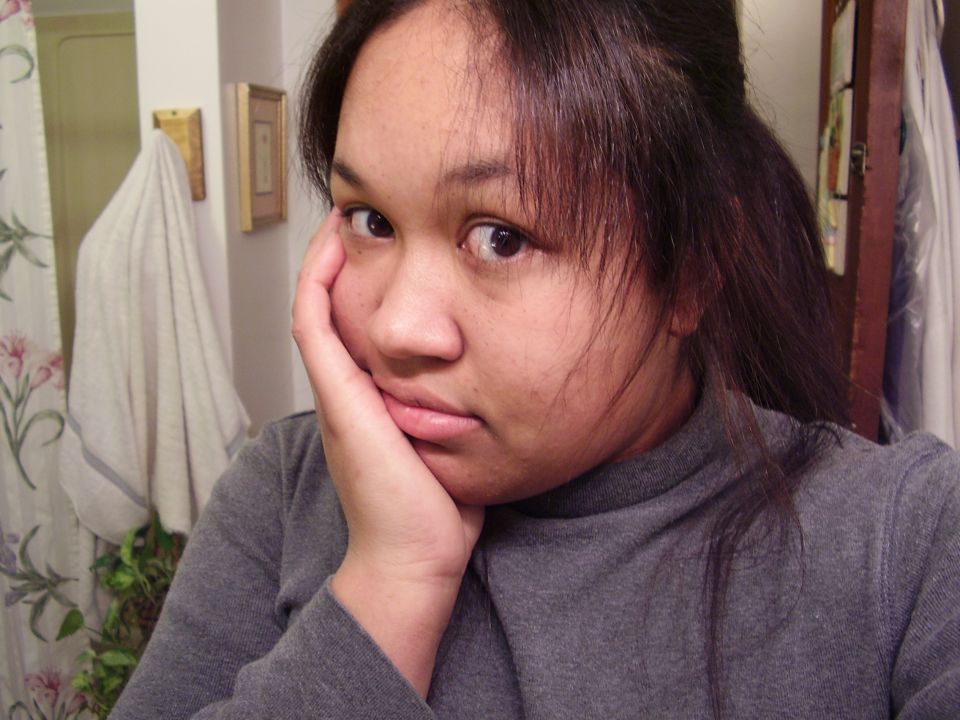 Woman resting her head on her hand, looking bored. Bathroom background with shower curtain and towel
