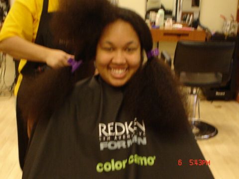 1997 Ford Taurus - A person smiles while their long dark hair is styled into pigtails, wearing a salon cape.