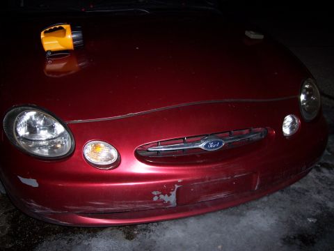 1999 Ford Taurus - Front view of a red 1999 Ford Taurus, showing damage to the bumper and hood.