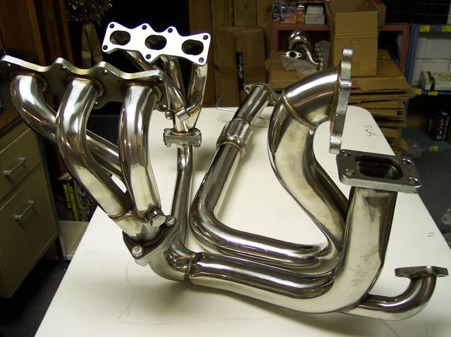 Chrome exhaust manifold with four pipes merging into one, attached to a turbo flange