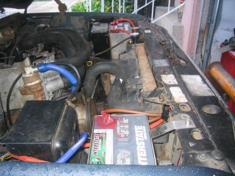1986 Ford Bronco - The engine bay of a vehicle, an Interstate battery and various hoses and components.