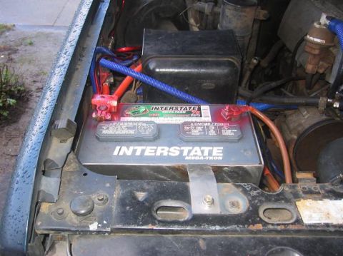 1986 Ford Bronco - Close-up of a vehicle's engine bay, focusing on the Interstate Mega-Tron battery and wiring.