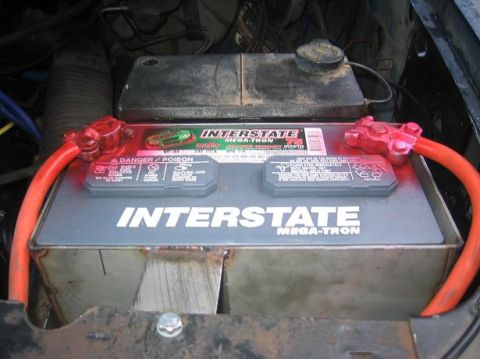 1986 Ford Bronco - A car battery with red cables and a metal bracket is visible in the engine bay.
