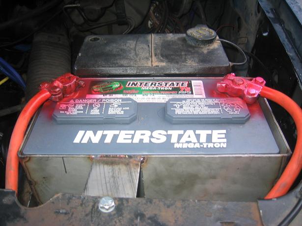 Interstate Mega-Tron car battery with red cables and a metal bracket