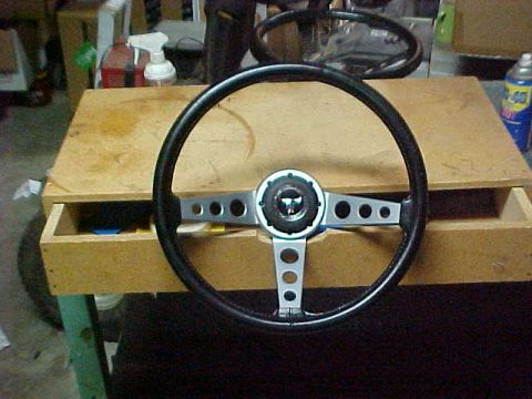 1973 Ford Ranchero - Three-spoke sport steering wheel with a black rim and brushed aluminum spokes drilled with round lightening holes, propped upright on a ply…