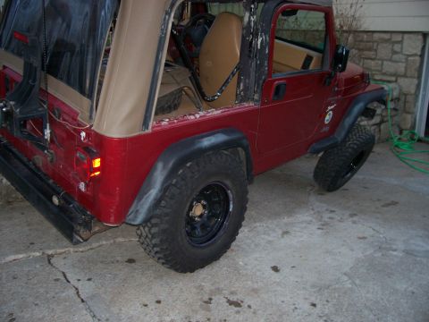 1998 Jeep TJ - This red Jeep Wrangler has its soft top removed, revealing the interior and rear tire.
