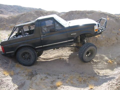 1992 Ford Bronco - This modified black Ford Bronco is shown off-roading on a sandy incline.