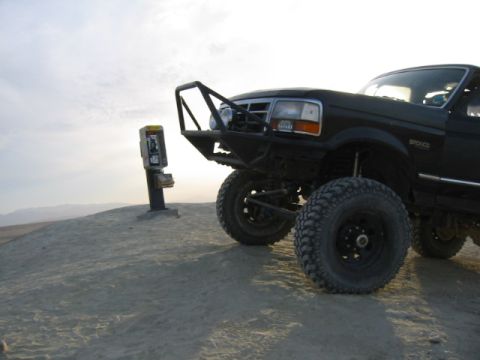 1992 Ford Bronco - A black 1992 Ford Bronco sits on a dirt hill next to a payphone under a cloudy sky.