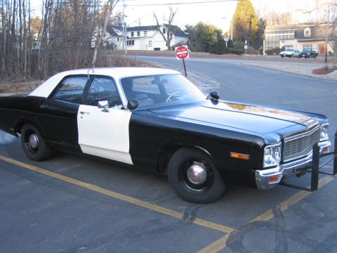 1991 Ford LTD Crown Victoria - restored black-and-white police-style sedan with a brush guard, parked in a lot near a stop sign and houses.