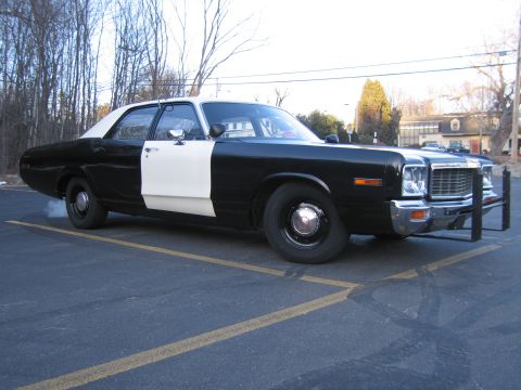 1991 Ford LTD Crown Victoria - black-and-white classic police sedan with a chrome grille, dual headlights and a black front push bar in a parking lot.