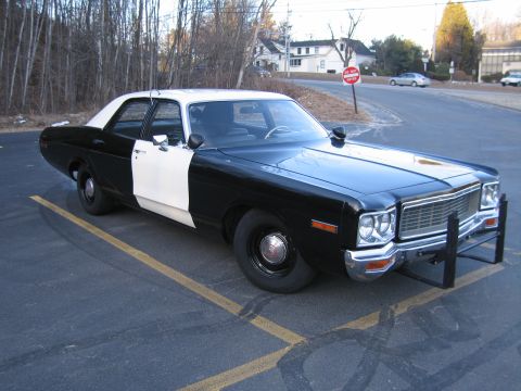 1991 Ford LTD Crown Victoria - black-and-white police-style sedan with chrome grille and push bar parked at dusk near houses and bare trees.