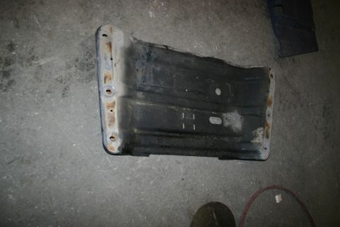 2003 Jeep TJ - A metal bracket with visible bolt holes and signs of rust sits on a concrete floor.