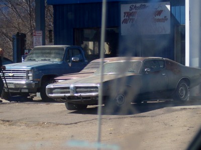 1972 Ford Ranchero - A weathered 1973 Dodge Charger sits in front of a business with a blue pickup truck behind it.