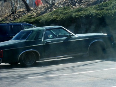 1972 Ford Ranchero - Side view of a dark green coupe with a vinyl top, parked next to another vehicle.