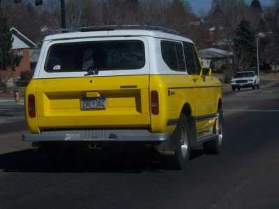 1972 Ford Ranchero - A yellow and white SUV drives down a street, with another vehicle visible in the distance.