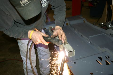 2003 Jeep TJ - A person is actively cutting a metal component with a plasma torch, generating a shower of sparks.