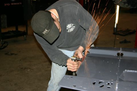 2003 Jeep TJ - A person works on a metal component, sparks flying from the grinding tool.