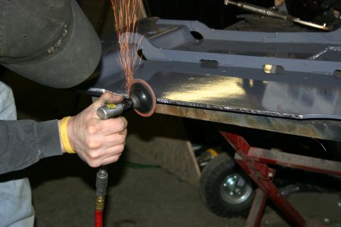 2003 Jeep TJ - A person uses an angle grinder to smooth the edge of a metal component, creating a shower of sparks.