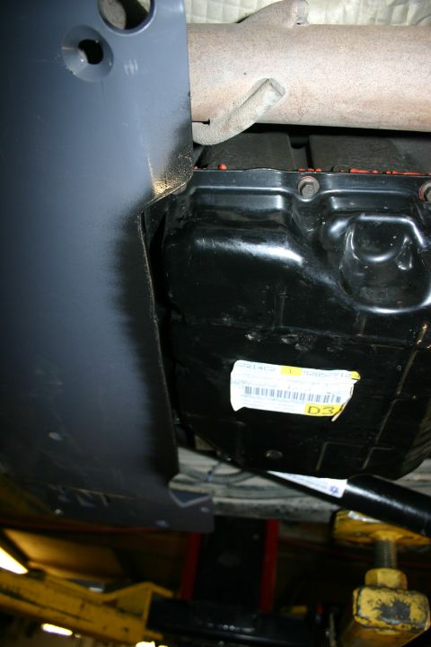 2003 Jeep TJ - A close-up view of a vehicle's undercarriage reveals a transmission pan and exhaust system.