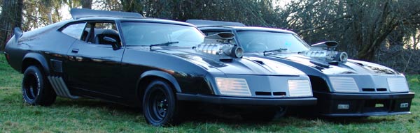 two black coupes with exposed superchargers on hoods, parked on grass
